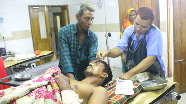 রক্তাক্ত অবস্থায় আহত নৈশপ্রহরী আজাহার আলীকে হাসপাতালে নেওয়া হচ্ছে – রাণীনগর, নওগাঁ।