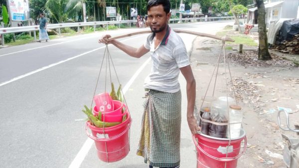 শরবতের বালতি কাঁধে নিয়ে হেঁটে চলেছেন শরবতওয়ালা কাওছার মিয়া